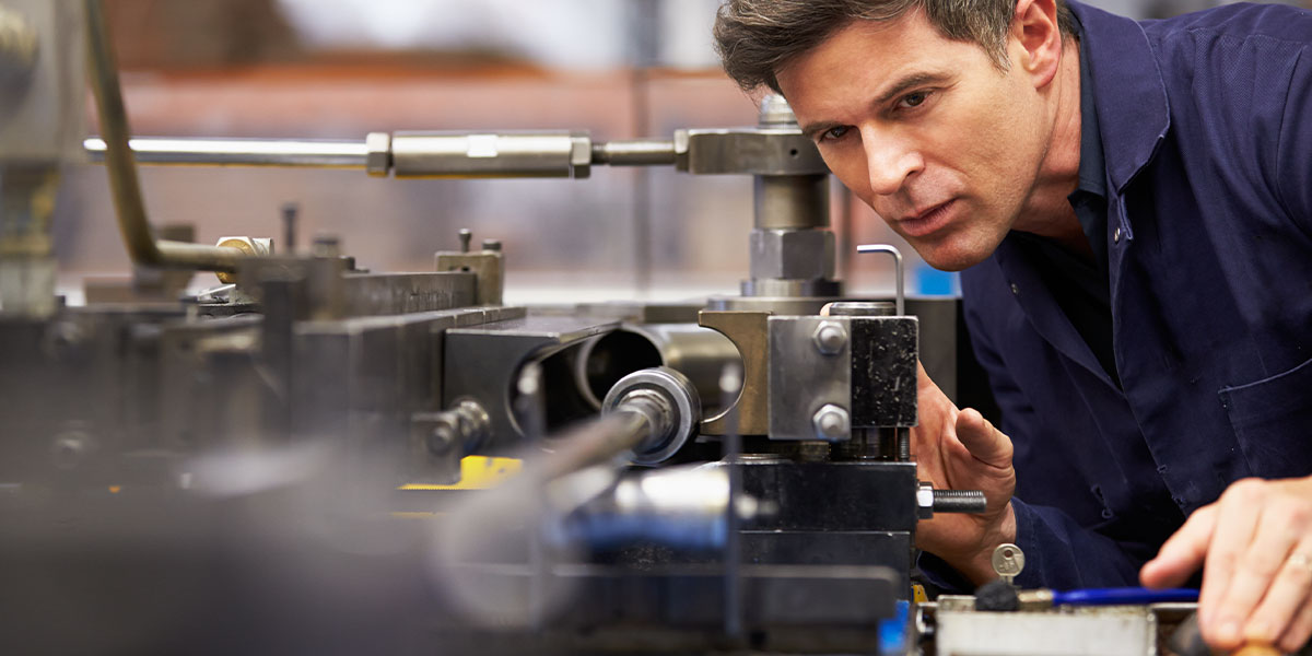 Engineer working with a large piece of machinery in a manufacturing facility.